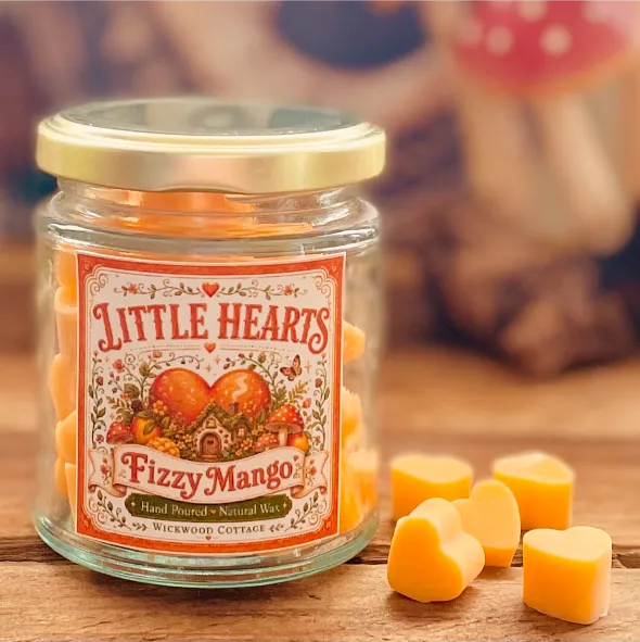 Jar of Wickwood Cottage Little Hearts Fizzy Mango wax melts with orange heart-shaped melts beside it on a rustic wooden surface.