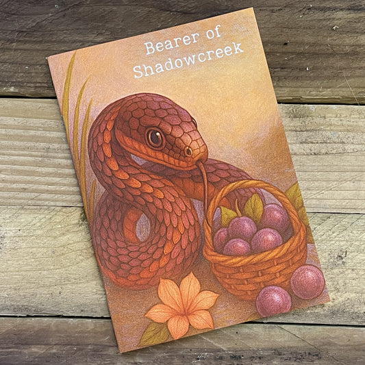 Notebook with the illustration of a snake and a basket of plumbs on a wooden surface