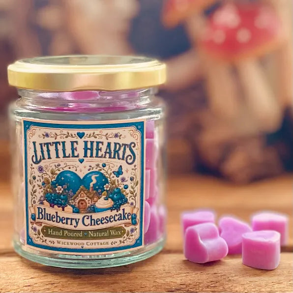 Jar of Wickwood Cottage Little Hearts Blueberry Cheesecake wax melts with lilac heart-shaped melts beside it on a rustic wooden surface.