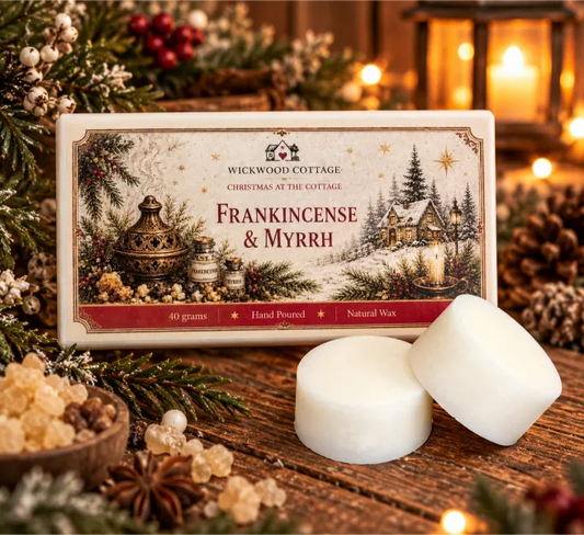 Wickwood Cottage Frankincense & Myrrh 40g hand-poured natural wax melts, featuring two chunky ivory wax discs beside festive cottage-inspired packaging on a rustic wooden table, surrounded by frankincense resin, evergreen branches, pinecones, winter berries and warm Christmas lantern lighting.