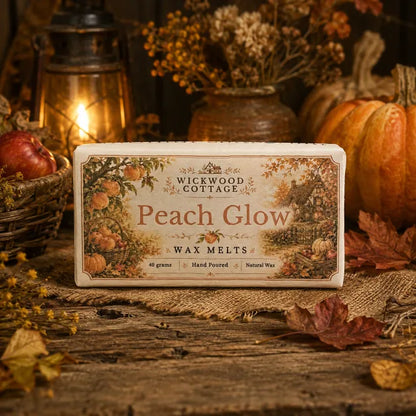 “Wickwood Cottage Peach Glow wax melts in a rustic autumn cottage setting with peaches, pumpkins, dried flowers and warm lantern light.”