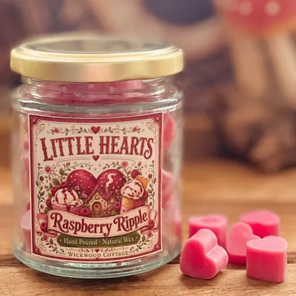 Jar of Wickwood Cottage Little Hearts Raspberry Ripple wax melts with pink heart-shaped melts beside it on a rustic wooden surface.