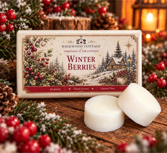 Wickwood Cottage Winter Berries 40g hand-poured natural wax melts, featuring two chunky ivory wax discs beside festive cottage-inspired packaging on a rustic wooden table, surrounded by frosted evergreen branches, red winter berries, pinecones and warm Christmas lantern lighting.