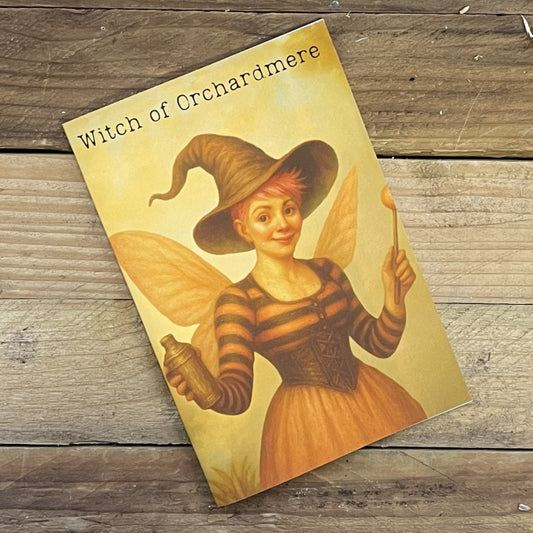 Book titled 'Witch of Orchardmere' featuring a fairy character on a wooden surface
