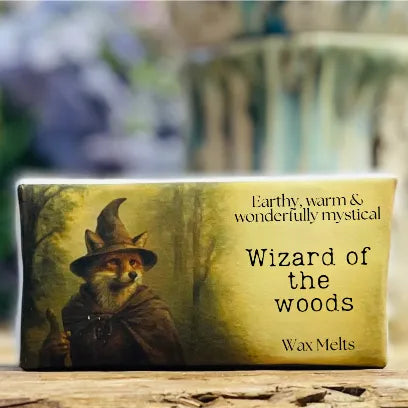 A close-up of the “Wizard of the Woods” wax melt packaging, featuring a painted fox wizard holding a staff in a misty forest. The label reads “Earthy, warm & wonderfully mystical” and “Wax Melts.” The artwork and textures create a charming, woodland fantasy feel, reflecting the brand’s strong smelling wax melts and cottagecore style.